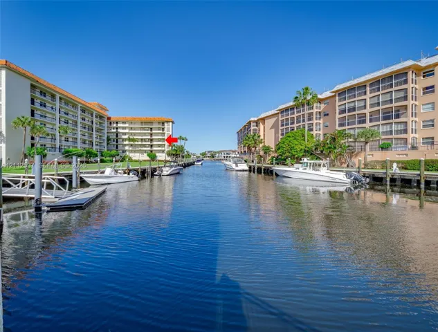 Waterfront condominium complex featuring concrete boat slips, direct canal access, and landscaped grounds