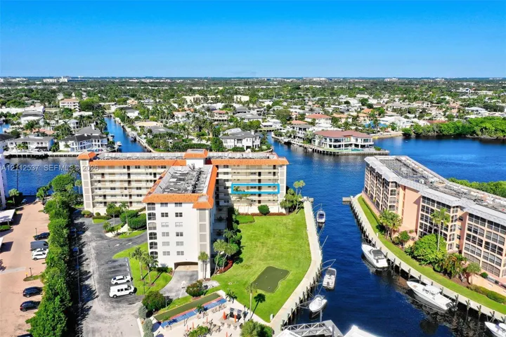 Multi-story residential building with terracotta-tiled roof, featuring water-front positioning, direct canal access, an on-site putting green, and manicured landscaping