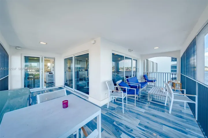 Covered balcony featuring multi-panel glass sliding doors, tiled flooring, recessed lighting, and metal railing