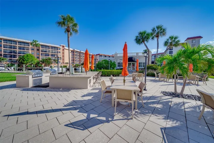 Outdoor patio area featuring stone-paver flooring, a built-in outdoor kitchen with stainless steel appliances, and mature palm trees