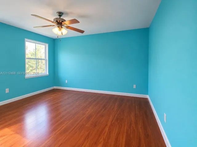Room featuring wood-finish flooring, a ceiling fan with integrated lighting, and a single-hung window