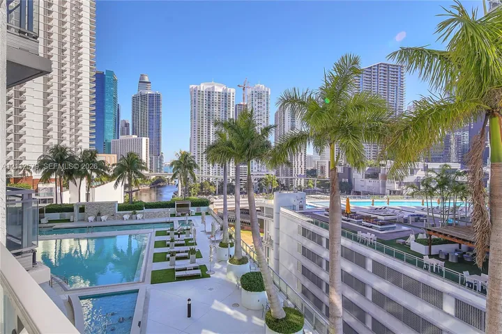 Outdoor terrace featuring a swimming pool, integrated landscaping with palm trees, and panoramic city skyline scenery
