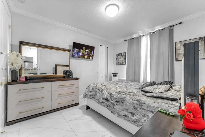 Room featuring large-format tile flooring with a neutral veined pattern, crown molding, and a central flush-mount ceiling light fixture