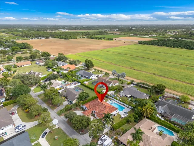 Aerial view of residential property featuring a clay tile roof, a private swimming pool, and a paved circular driveway