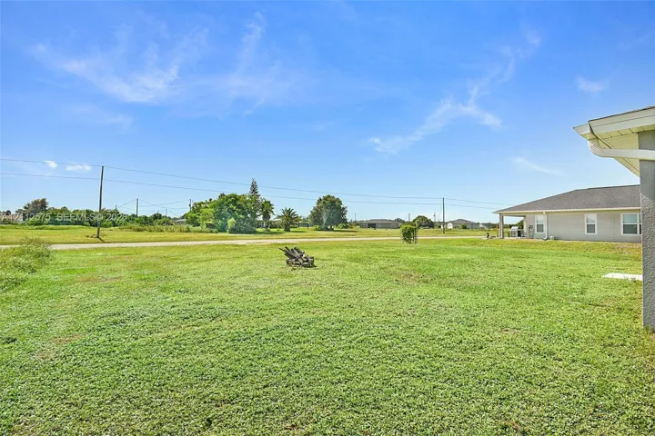 Expansive grass yard featuring open terrain and mature trees