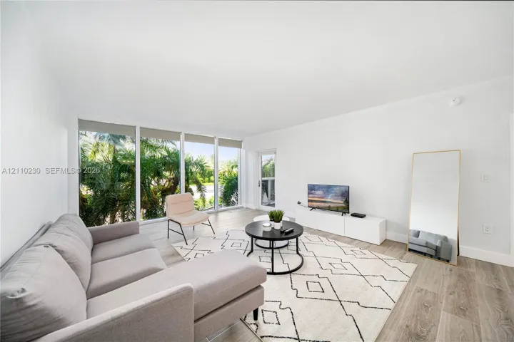 Living area featuring wood-finish flooring, floor-to-ceiling windows, and glass-paneled entry door