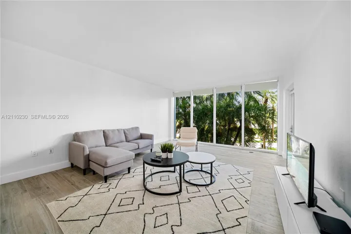 Expansive living area featuring floor-to-ceiling windows, wood-finish flooring, and neutral wall tones