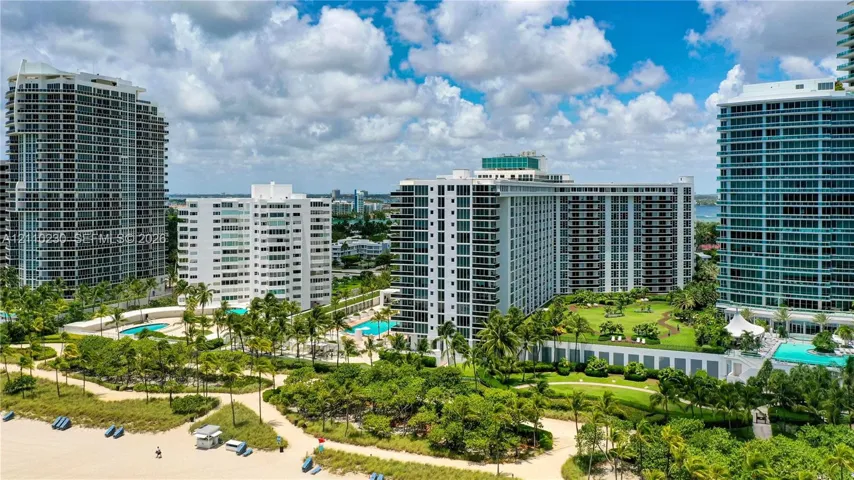 High-rise residential towers featuring private swimming pools, landscaped lawn areas, and direct sandy beach access