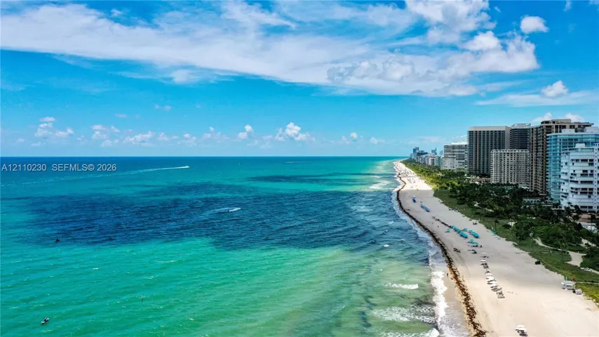 Aerial perspective of the coastline featuring expansive ocean frontage, a sandy beach, and high-rise developments