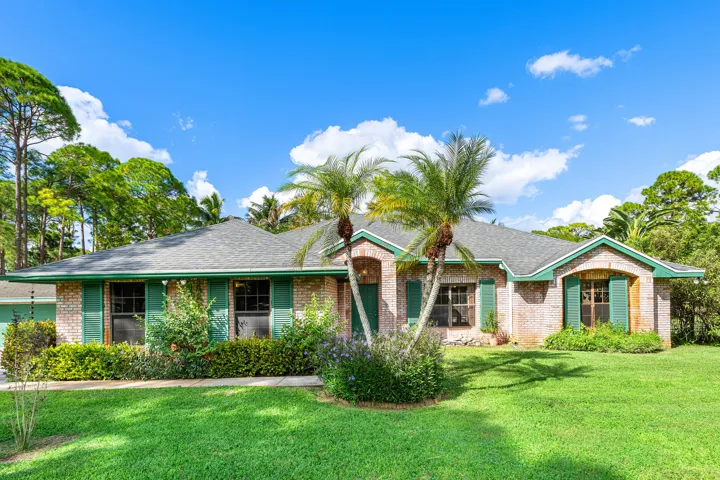 Single-story brick exterior featuring a shingled hip roof, decorative shutters, and an arched entryway