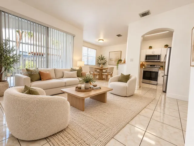 Open-concept living space with polished tile flooring, floor-to-ceiling vertical blinds, recessed lighting, and a kitchen featuring an arched entryway and stainless steel appliances