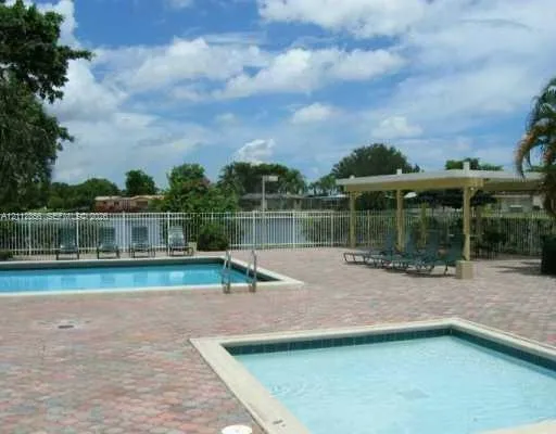 Outdoor area featuring a swimming pool, separate spa, paver patio, and covered pavilion enclosed by metal fencing