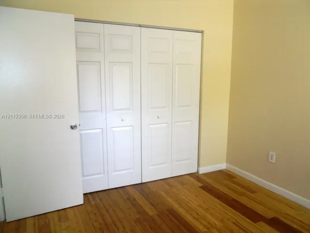 Wood-finish flooring paired with white four-panel bi-fold closet doors and a matching white swinging door