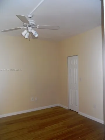 Room featuring wood-finish flooring, a white ceiling fan with integrated light fixture, and a white bi-fold closet door