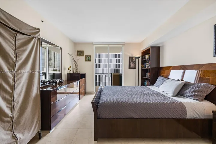 Sliding glass door opening to a balcony, stone-finish flooring, and high ceilings