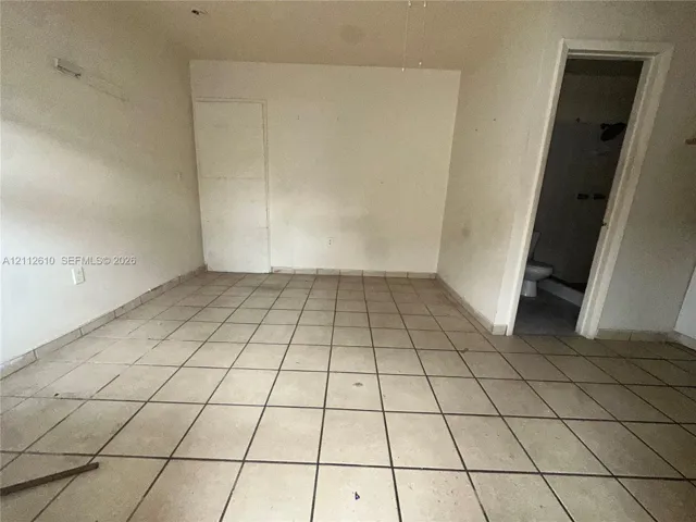 Interior room featuring light-toned ceramic tile flooring and a doorway leading to a tiled bath area