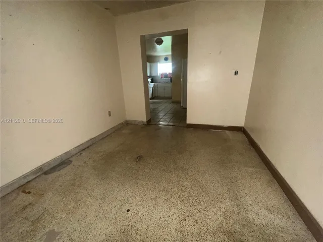 Interior space featuring terrazzo flooring and a threshold leading to a secondary room with tiled flooring and white cabinetry