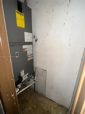 Dedicated mechanical closet featuring a vertical HVAC unit with associated plumbing and a wire metal shelving rack