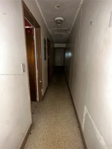 Hallway featuring textured ceiling, flush-mount light fixture, and tile flooring