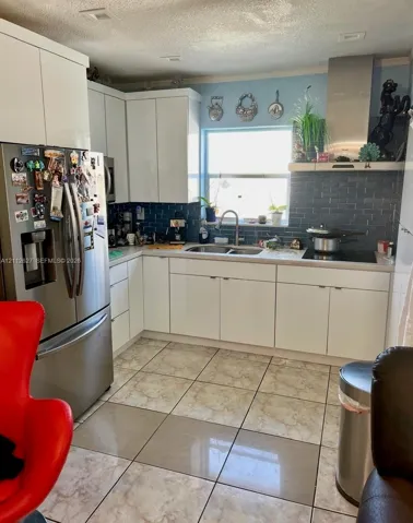 Kitchen featuring white cabinetry, stainless steel appliances, dark subway tile backsplash, and ceramic floor tiling