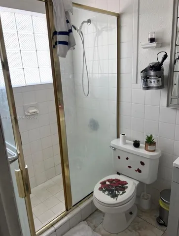 Walk-in shower enclosure featuring gold-tone metal framing and integrated glass block window