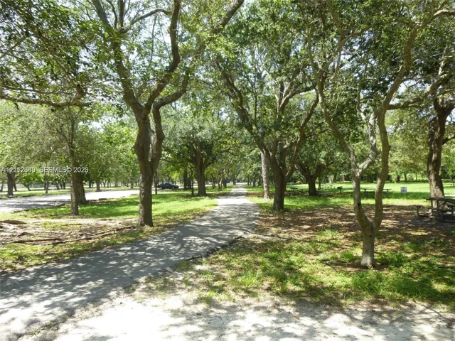 Paved walking path winding through a landscape of mature hardwood trees and grassy grounds