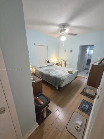 Bedroom featuring wood-finish flooring, vertical blinds, and a ceiling fan with light fixture