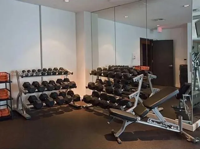 Dedicated fitness space featuring mirrored walls and durable rubberized flooring