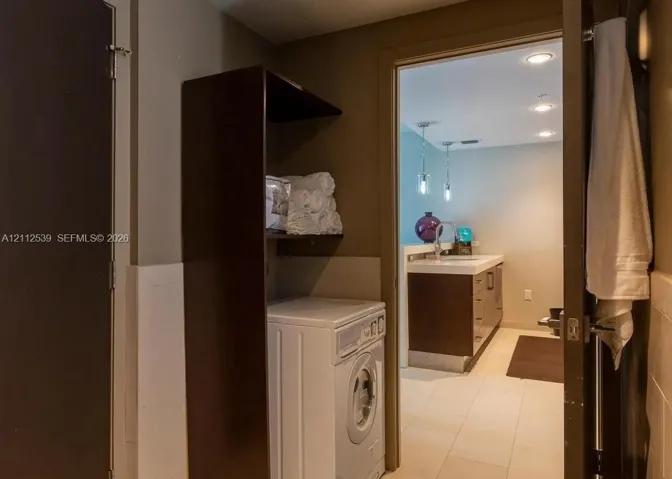 Laundry area featuring custom floor-to-ceiling built-in cabinetry and tile flooring