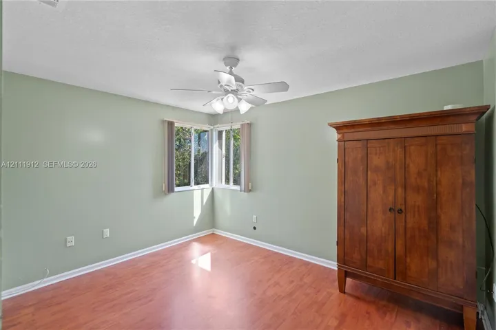 Interior space featuring wood-finish flooring, corner windows, and a ceiling-mounted light fixture with a fan