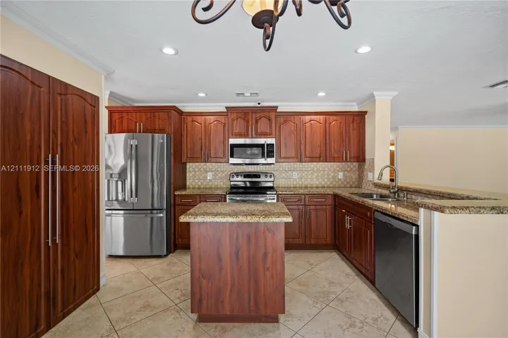 Kitchen featuring cherry-finish cabinetry, stainless steel appliances, stone-surface countertops, a center island, and tile flooring