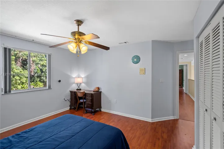 Room with wood-finish flooring, ceiling fan with integrated lighting, dual-pane window, and louvered bi-fold closet doors