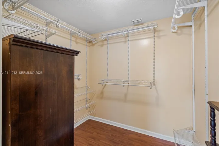 Walk-in closet featuring wood-finish flooring and tiered white wire shelving