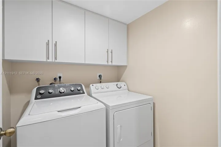 Laundry area featuring white cabinetry with brushed-metal pulls and dedicated utility hookups