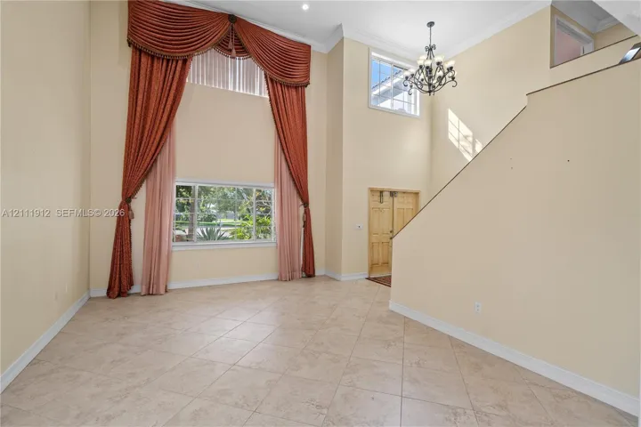 Two-story foyer featuring tile flooring, a multi-tiered chandelier, and large windows with transom