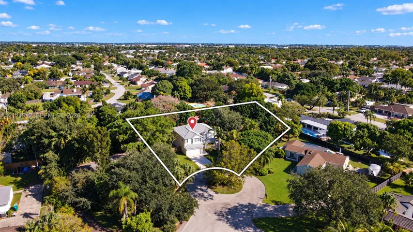 Aerial perspective of a multi-story residence situated on a corner lot featuring a concrete driveway, two-car garage, and established perimeter landscaping