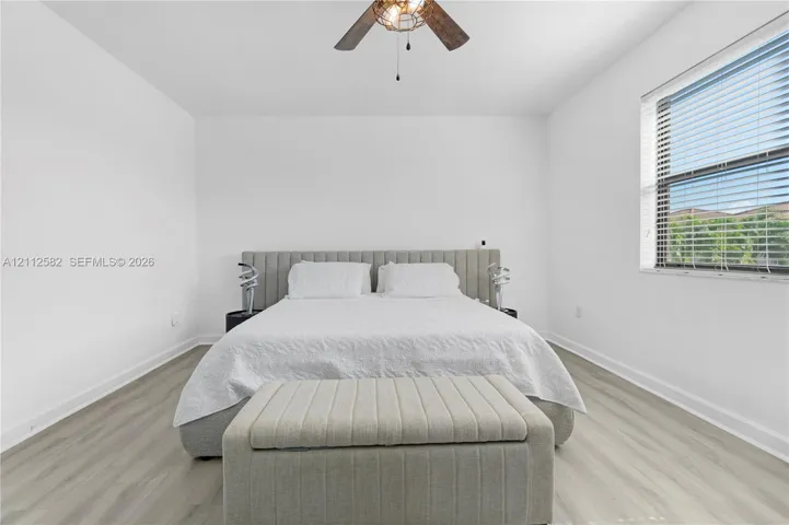 Neutral-toned wood-finish flooring, white walls, and a ceiling-mounted light fixture with a fan