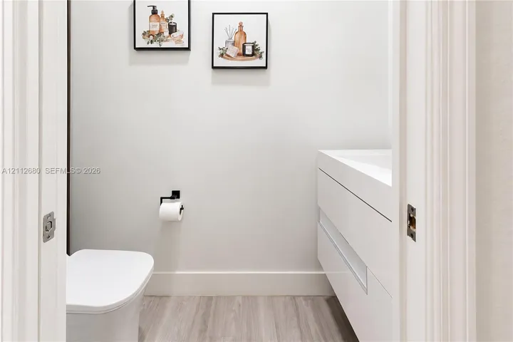 Floating vanity with integrated sink, wood-finish flooring, and matte black hardware