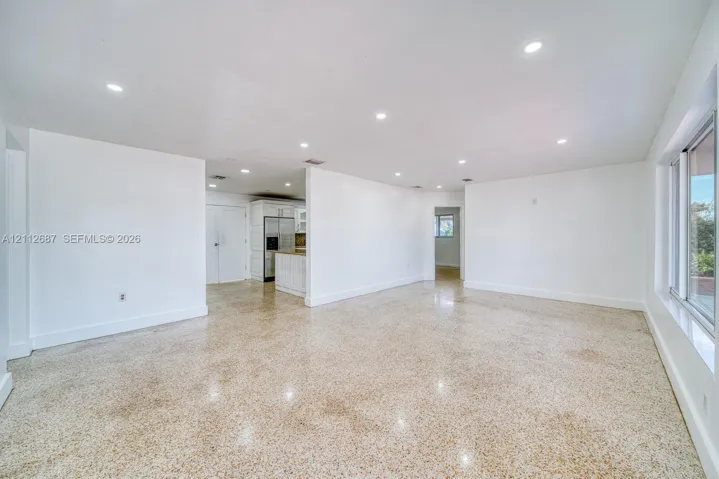 Open-concept interior featuring polished aggregate flooring, recessed lighting, and large-format sliding windows
