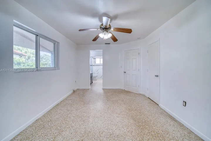 Interior space featuring neutral wall paint, terrazzo flooring, a ceiling fan with integrated lighting, and two six-panel interior doors