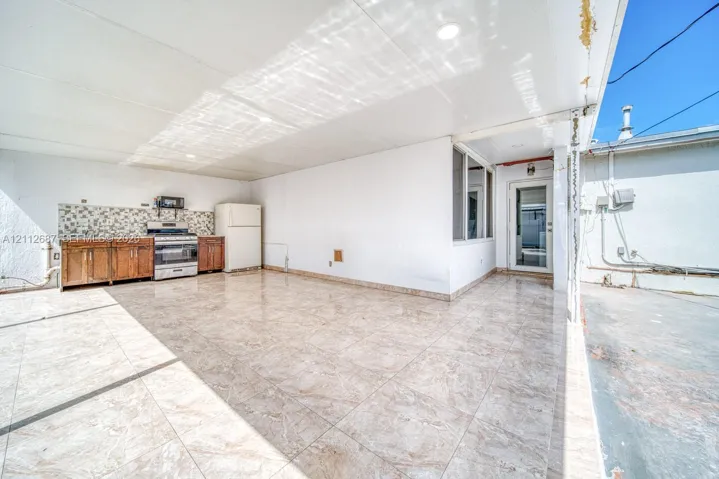 Covered outdoor area featuring tile flooring, built-in cabinetry, a stone-patterned backsplash, and recessed lighting