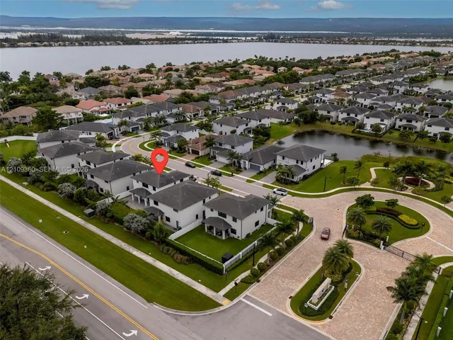 Aerial perspective of residential property featuring a multi-story exterior, attached garage, fenced perimeter, and proximity to expansive water frontage