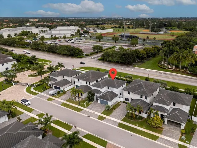 Multi-level residence featuring a concrete tile roof, light-toned exterior finish, and a paver driveway leading to a multi-car garage