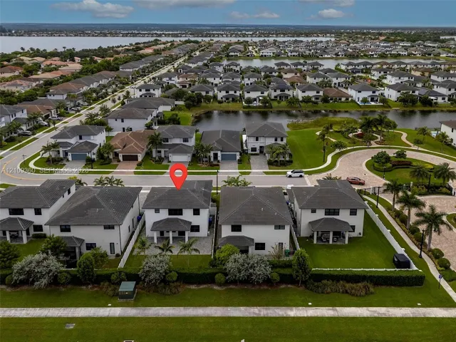 Two-story residence featuring a hipped roof, covered rear patio, integrated two-car garage, and a fenced backyard