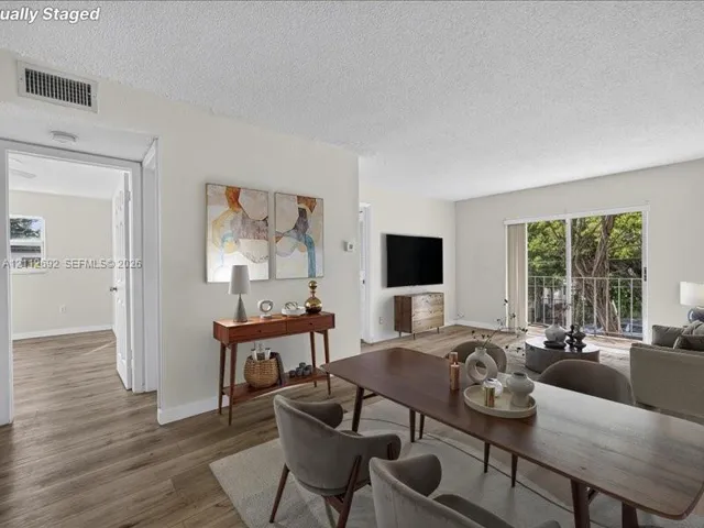 Open-concept interior featuring wood-finish flooring, sliding glass doors to a balcony, and white-painted walls