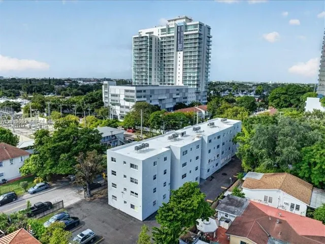 Multi-story residential building featuring a flat roofline, neutral exterior cladding, and dedicated surface parking