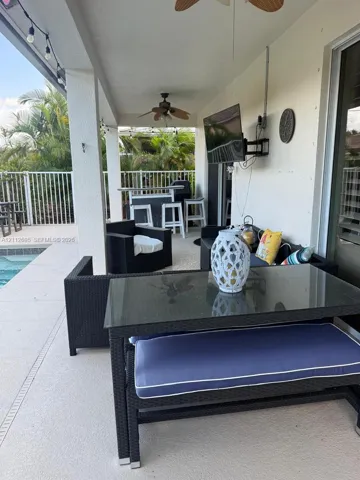 Covered patio featuring a concrete deck, dual ceiling fans, recessed lighting, and a white metal perimeter fence