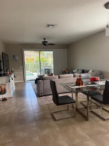 Large-format tile flooring, recessed lighting, ceiling fan, and sliding glass doors with access to a fenced outdoor area
