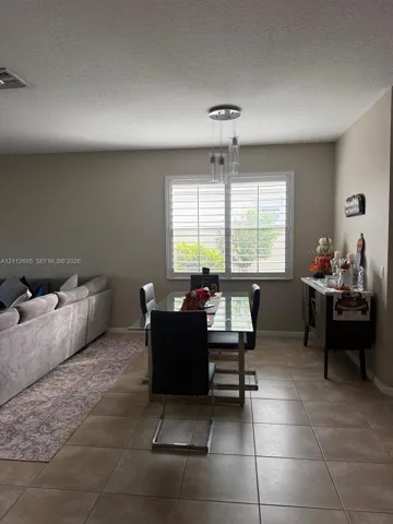 Ceramic tile flooring, multi-pane window with plantation shutters, and a three-light glass pendant fixture