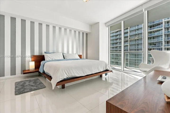 Floor-to-ceiling windows, polished tile flooring, and integrated wall-mounted bedside shelving